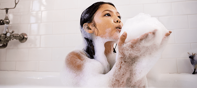 Girl taking a bubble bath in soft water from a Culligan Water Softener